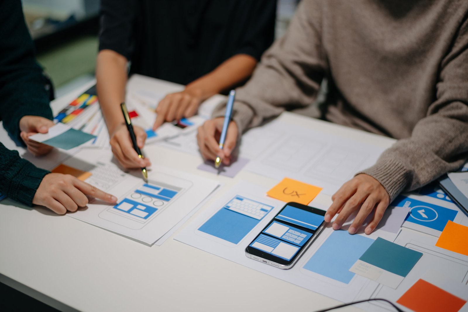 Close up view of UI developer team brainstorming on their project with laptop, smartphone and digital tablet. Creative digital development agency.