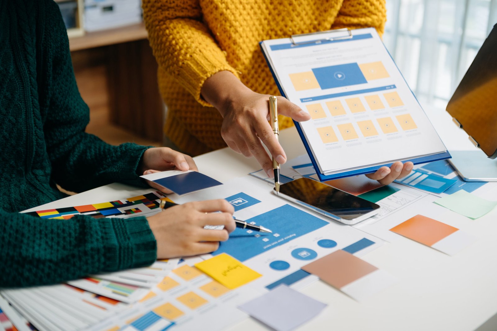 UX developer and ui designer brainstorming about mobile app interface wireframe design with customer breif and color code at modern office.