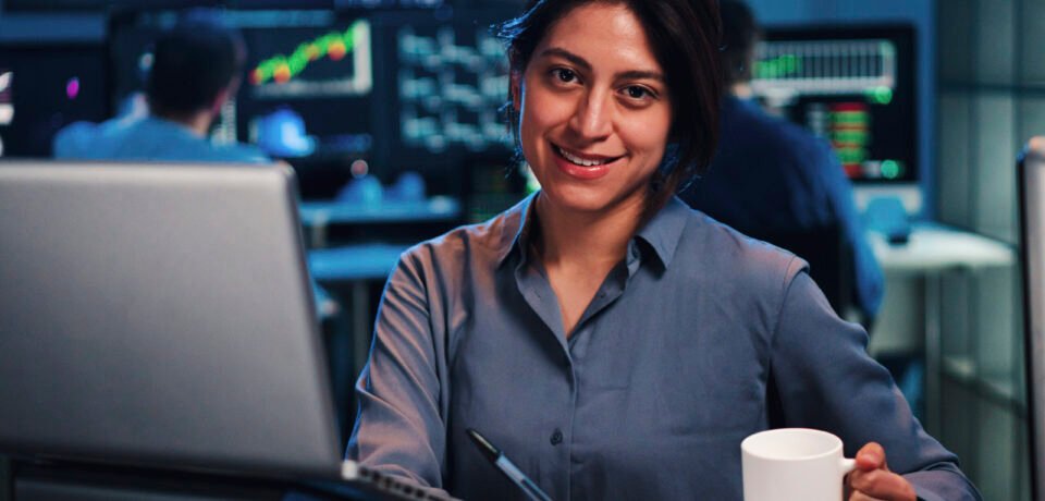 Young business female or broker working on finance trading with laptop computer. Investiment woman looking at camera at office. Economy concept. High quality photo