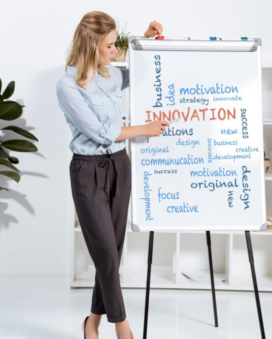 businesswoman looking and pointing at presentation on white board in office businesswoman looking and pointing at presentation on white board in office