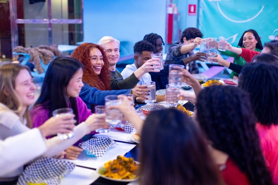 Happy multiethnic friends toasting drinks at restaurant friendship and celebration concept Happy multi ethnic friends raising glasses of water and toasting while sitting at a restaurant table, celebrating together