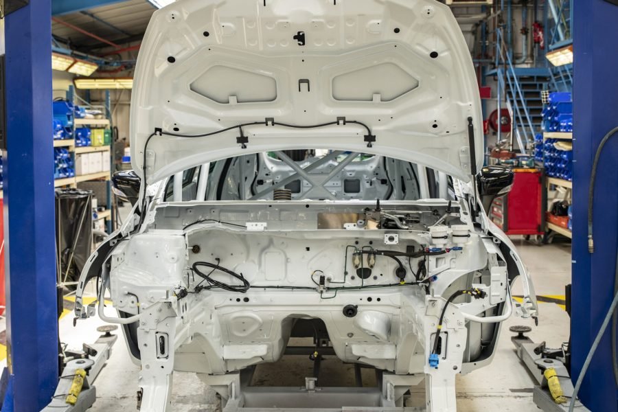 New car with open hood at a factory New white car with open hood at a factory