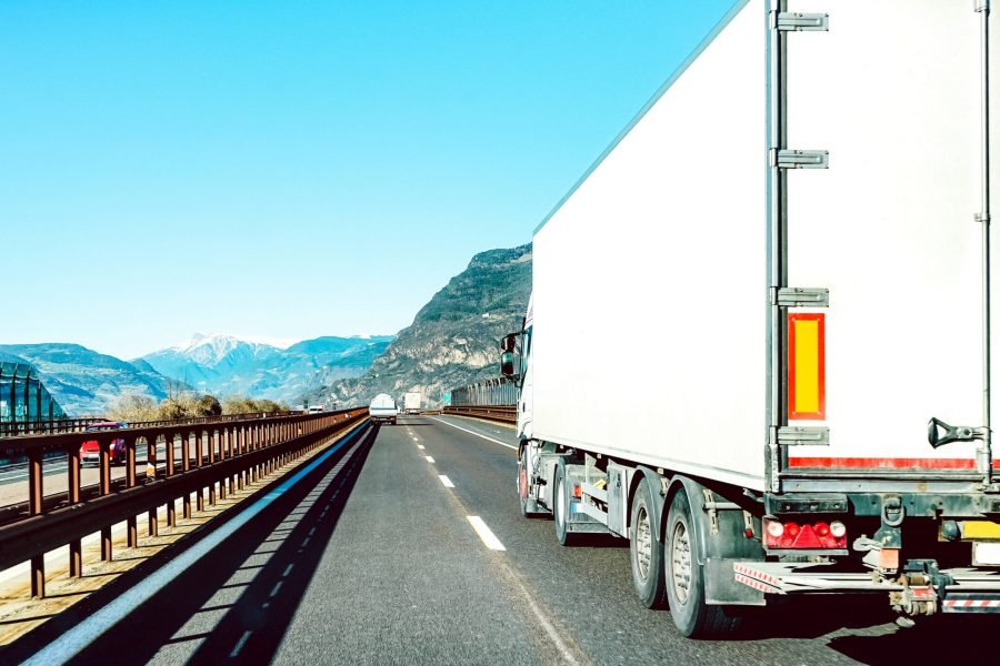 Semi truck speeding on empty highway line - Transport logistic concept with semitruck container driving on speedway - Focus on central part of background